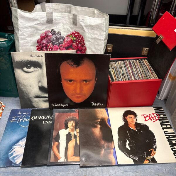 Mixed vinyl records lot with Phil Collins, Michael Jackson and Queen sleeves beside a red singles box