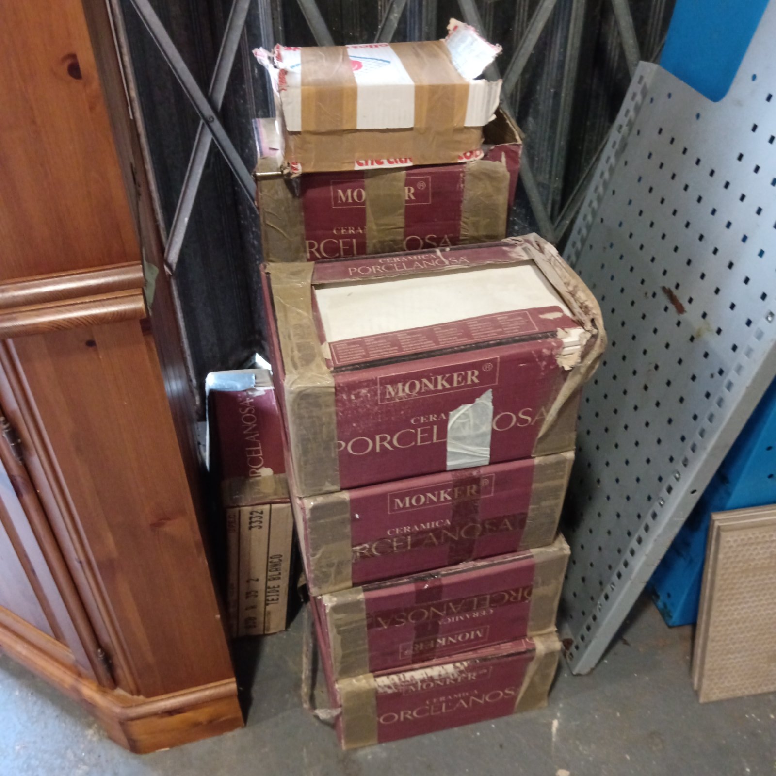 Stacked burgundy boxes of Monker Ceramica Porcelanosa porcelain tiles, taped and worn
