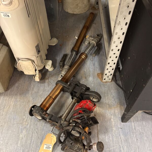Motorcycle front forks with triple clamp and handlebar switchgear on a workshop floor