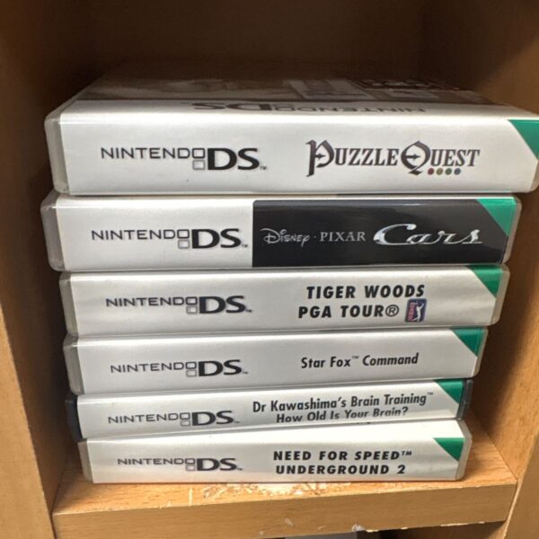 Stack of six Nintendo DS game cases including Puzzle Quest and Need for Speed Underground 2