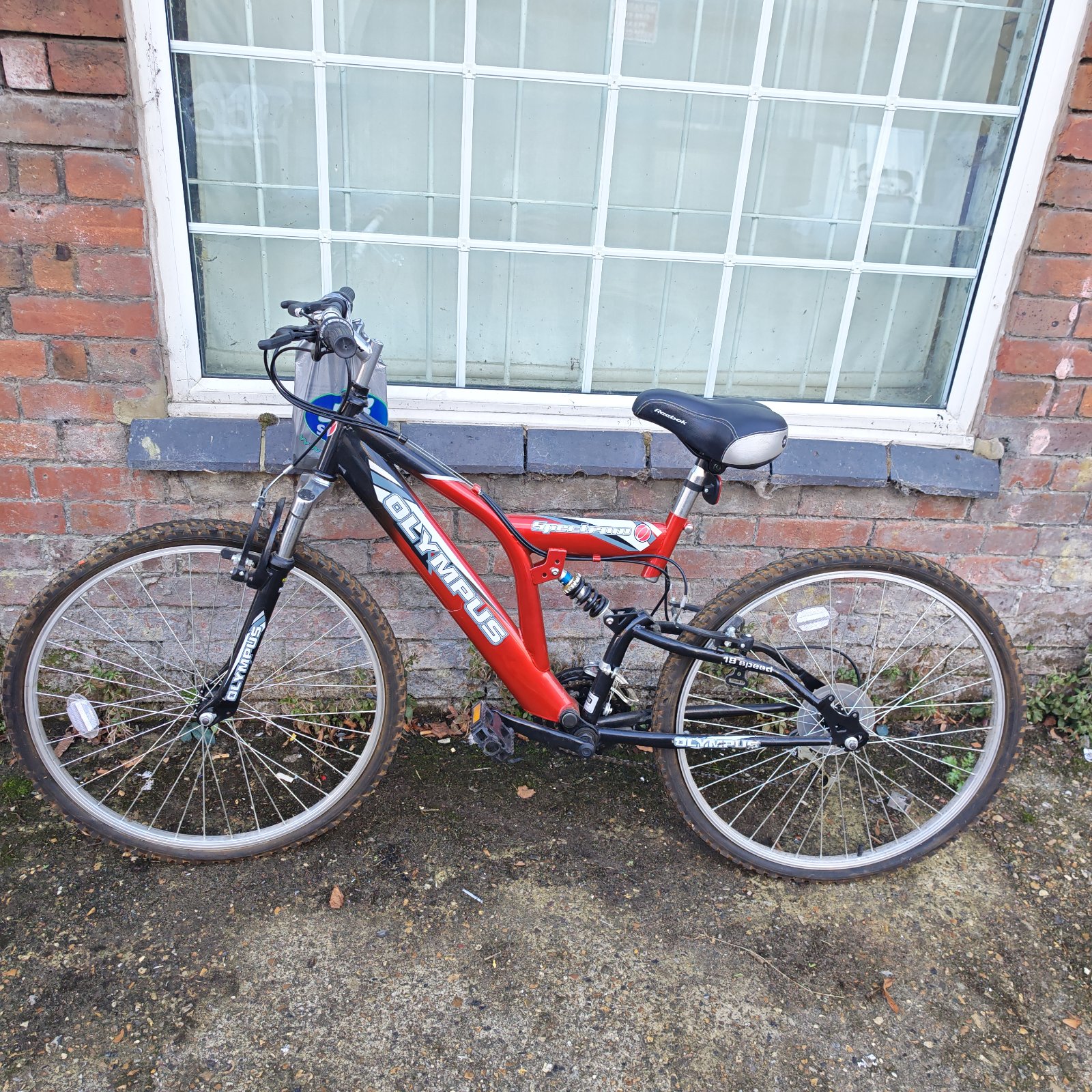 Red and black Olympus Spectrum full suspension mountain bike with silver wheels