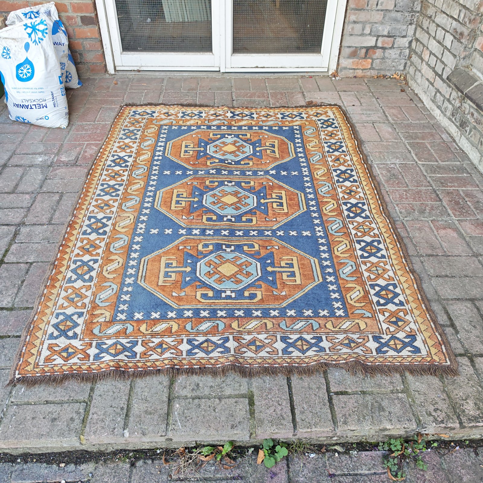 Vibrant orange and blue geometric area rug on a tiled surface.