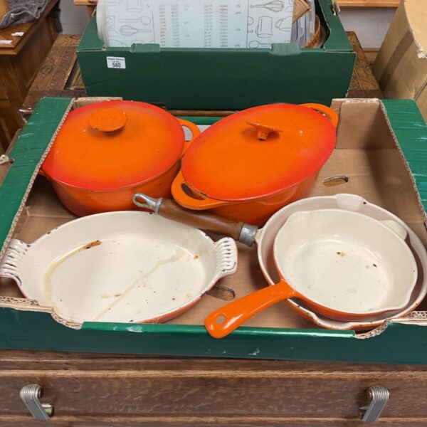 Tray of orange enamelled cast iron casseroles, oval dish and skillet