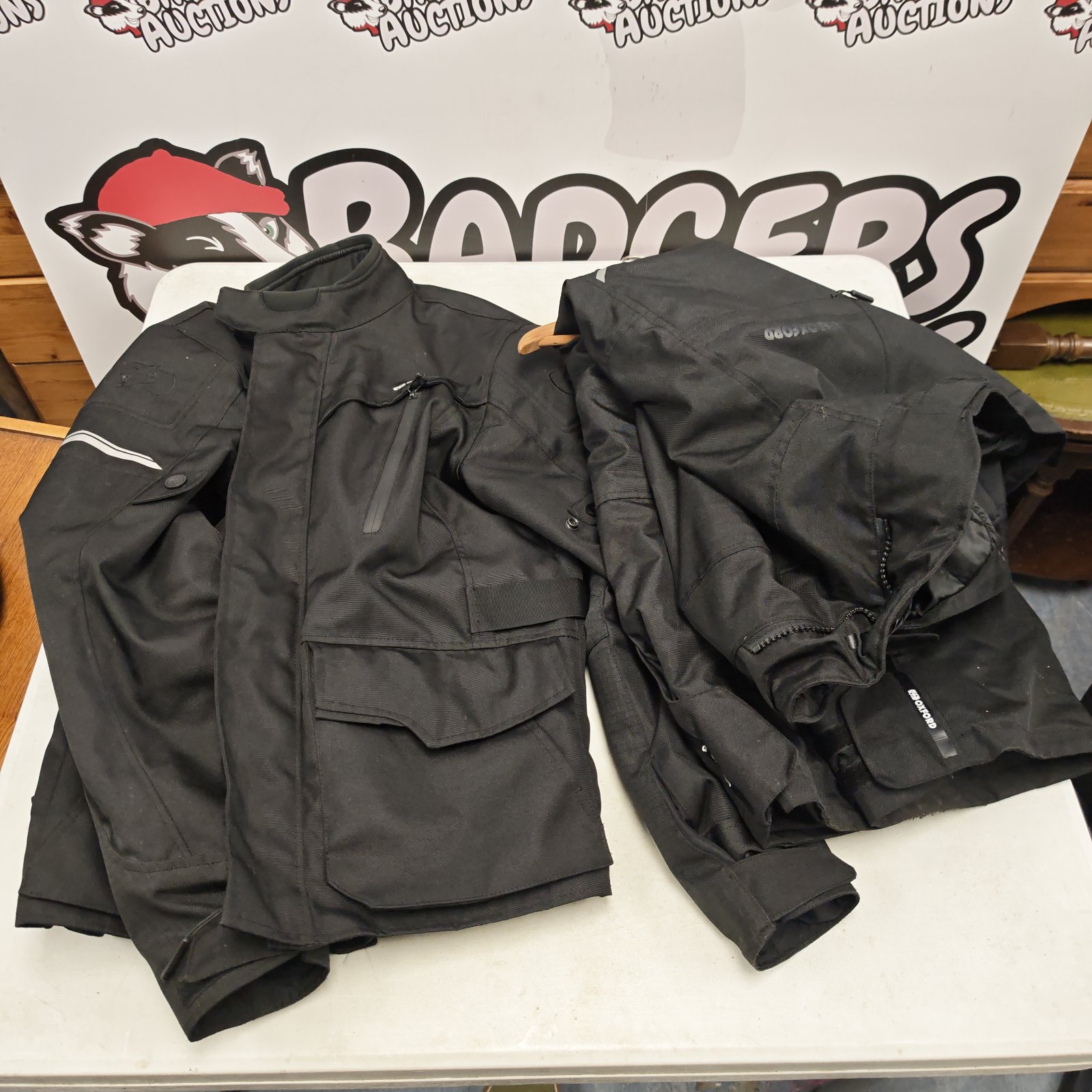 Black Oxford waterproof motorcycle jacket and trousers, size M, laid on a table