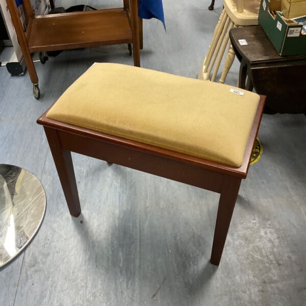 Vintage padded piano stool with patterned seat and wooden legs.