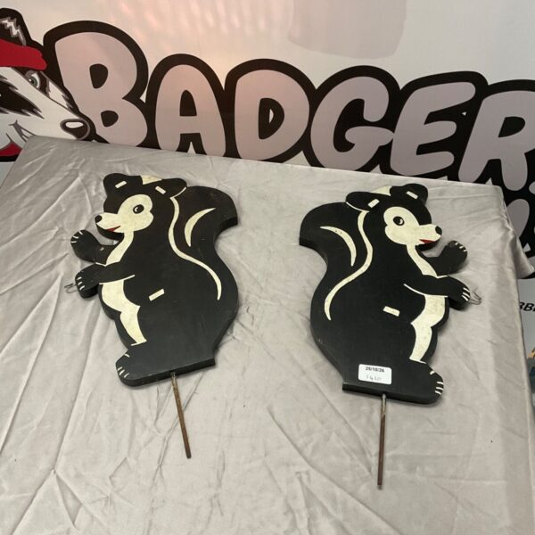 Pair of painted wooden skunk garden art pieces with metal stakes