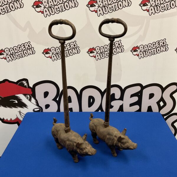 Pair of cast iron pig door stops with tall iron handles on blue surface