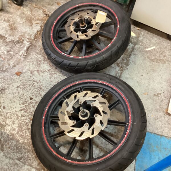 Pair of black spoked motorcycle wheels with brake discs and road tyres