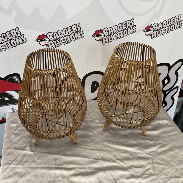 Pair of natural rattan teardrop lanterns with woven rims on a grey cloth
