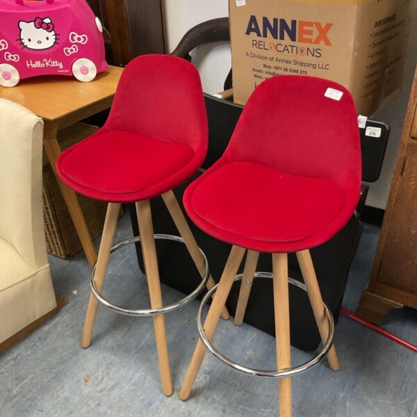 Pair of red velvet bar stools with wooden legs and chrome footrests