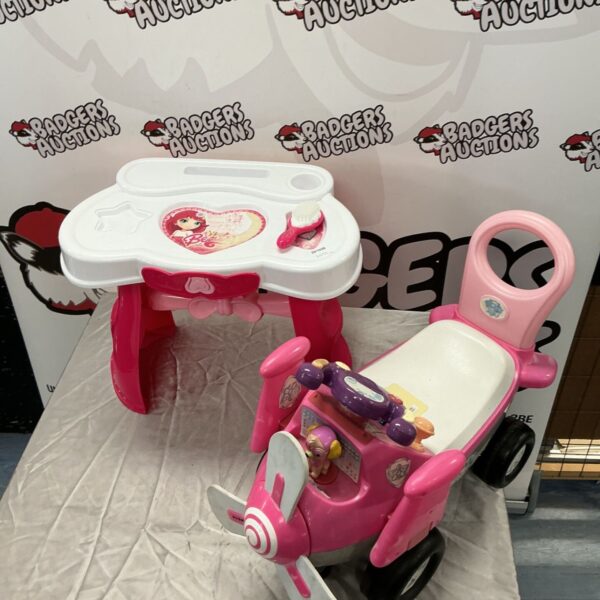 Pink Paw Patrol ride-on plane toy beside a Fashion Girls kids table