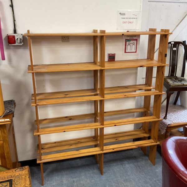 Freestanding pine slatted bookshelves with multiple open tiers against a white wall