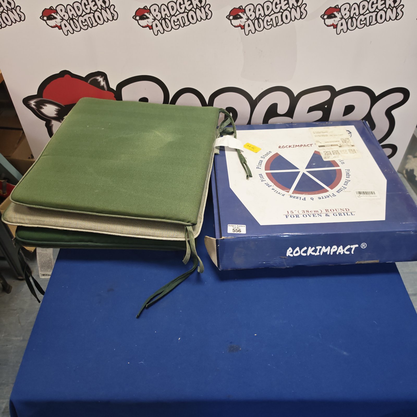 Pizza stone in box with four green seat cushions.