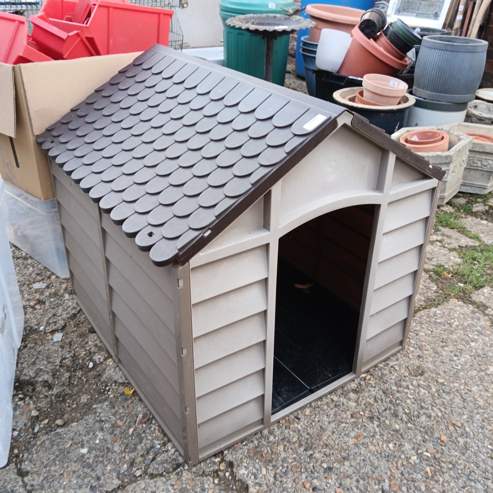 Grey plastic dog house in a garden setting.