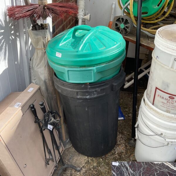 Two plastic dustbins in a garden setting, showing signs of weathering.