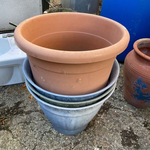Stack of four terracotta plastic garden planters for outdoor use.