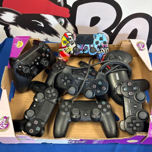 Mixed lot of vintage PlayStation and Sega gaming controllers.