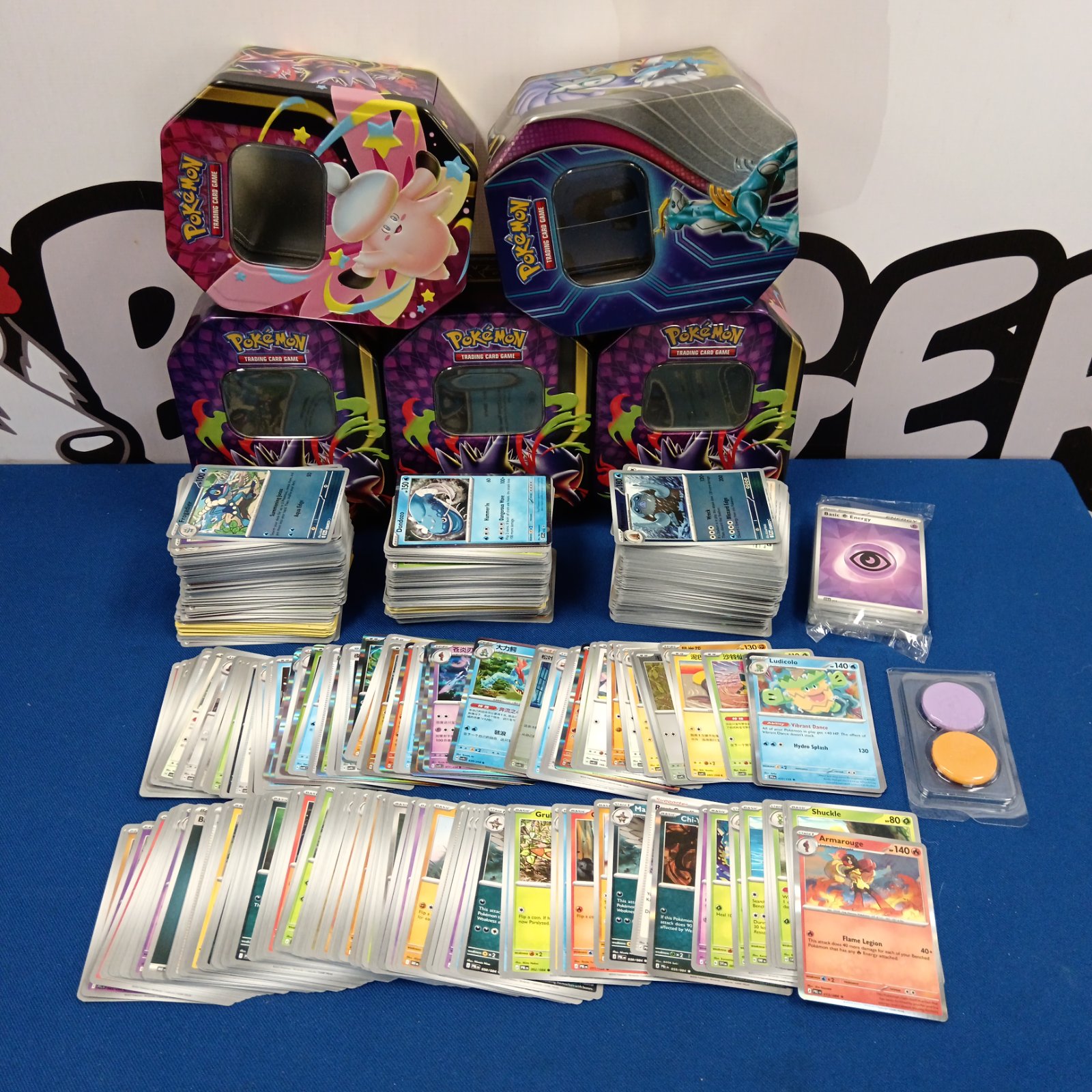 Pokémon card collection in tins with holographic cards visible.