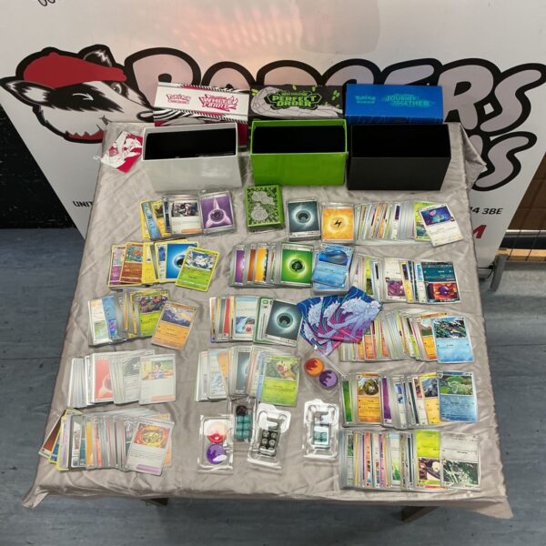 Large lot of Pokémon trading cards with storage boxes and accessories laid out on a table
