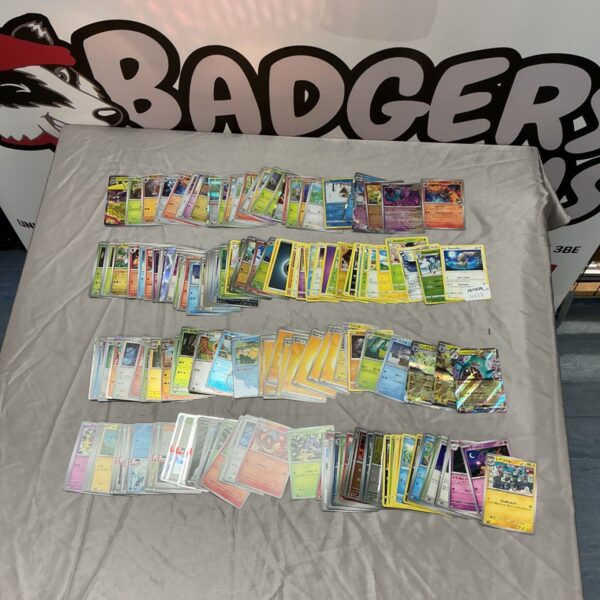 Large mixed lot of Pokémon trading cards laid out in rows on grey cloth