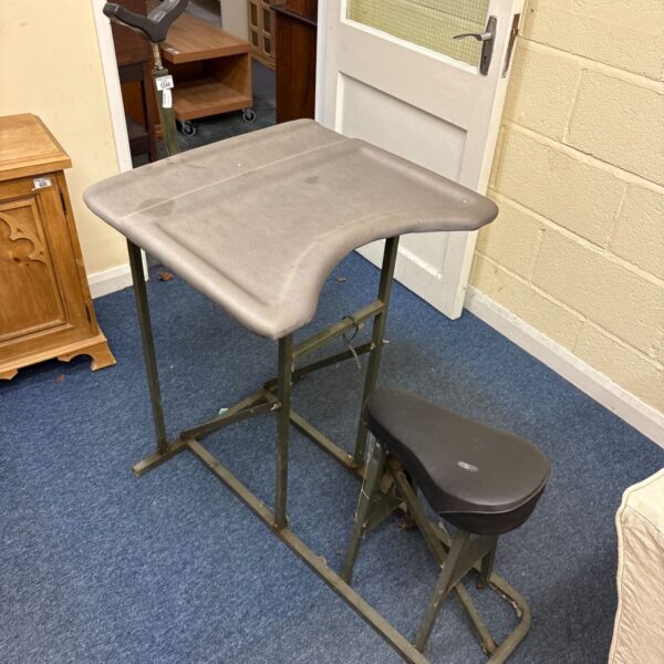 Portable metal-framed shooting bench with grey top and attached dark brown seat