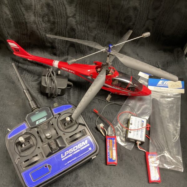 Red E-flite Blade 120 radio control helicopter beside LP5DSM transmitter and spares