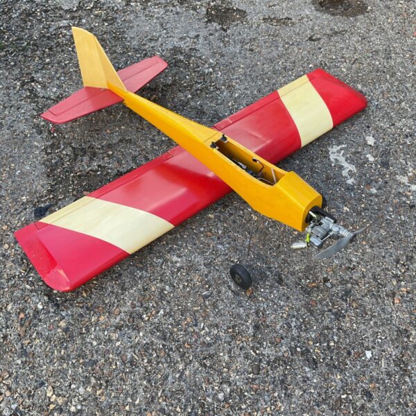 Red and yellow RC balsa airplane model with glow engine.