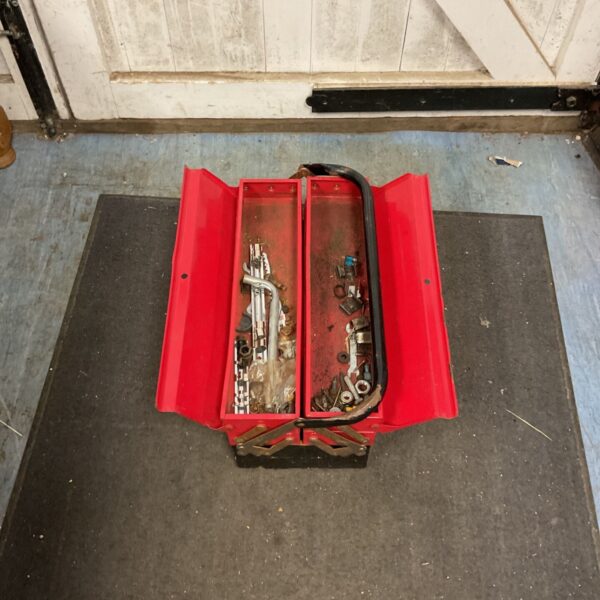 Open red cantilever toolbox displaying interior compartments and tool storage.
