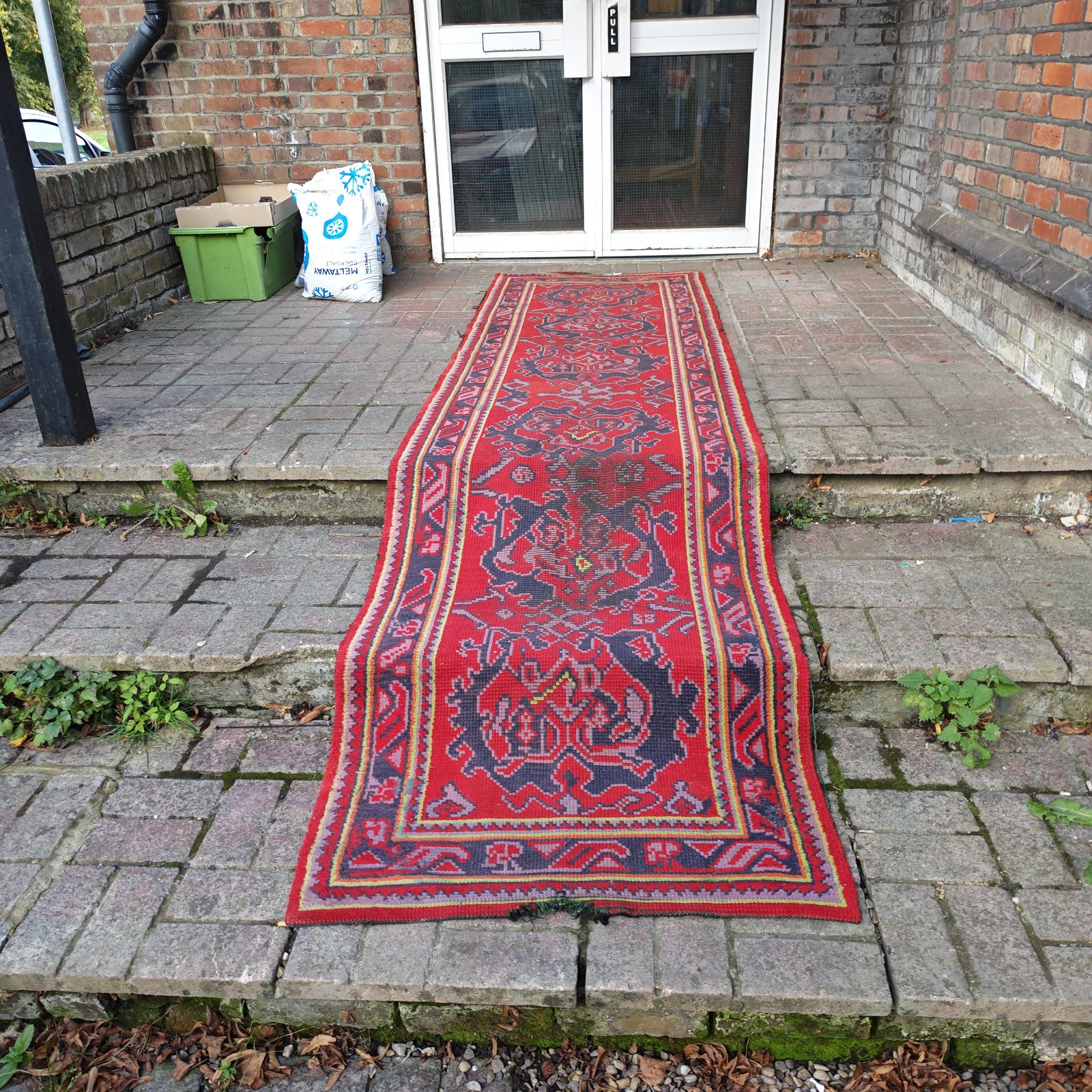 Vintage red and navy runner rug displayed outdoors.