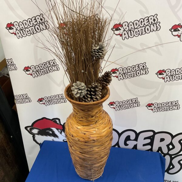 Tall woven reed vase with pine cones and dried grasses.