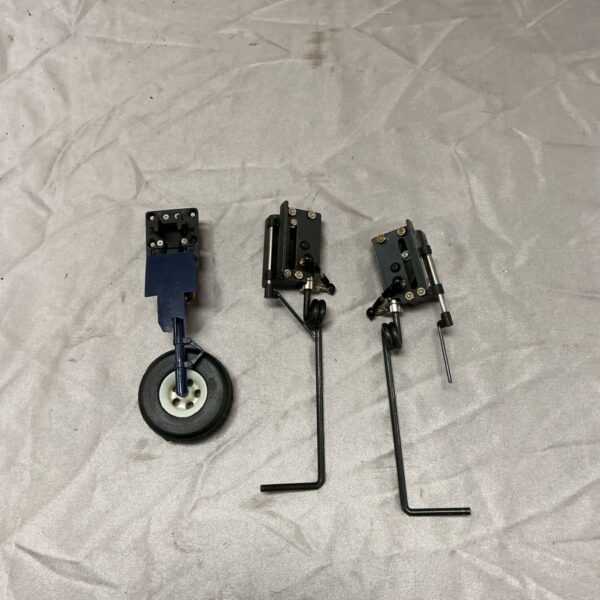 Three model aircraft undercarriage units laid out on a light grey fabric surface