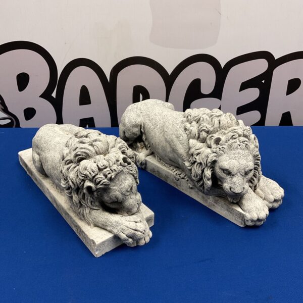 Pair of grey cast stone reclining lions on plinths, Canova style garden statues