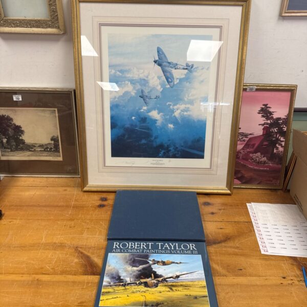Robert Taylor aviation print with accompanying book on a wooden table.