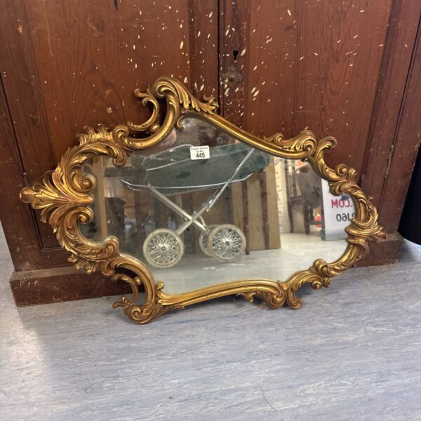 Vintage rococo gilt framed mirror with ornate detailing.