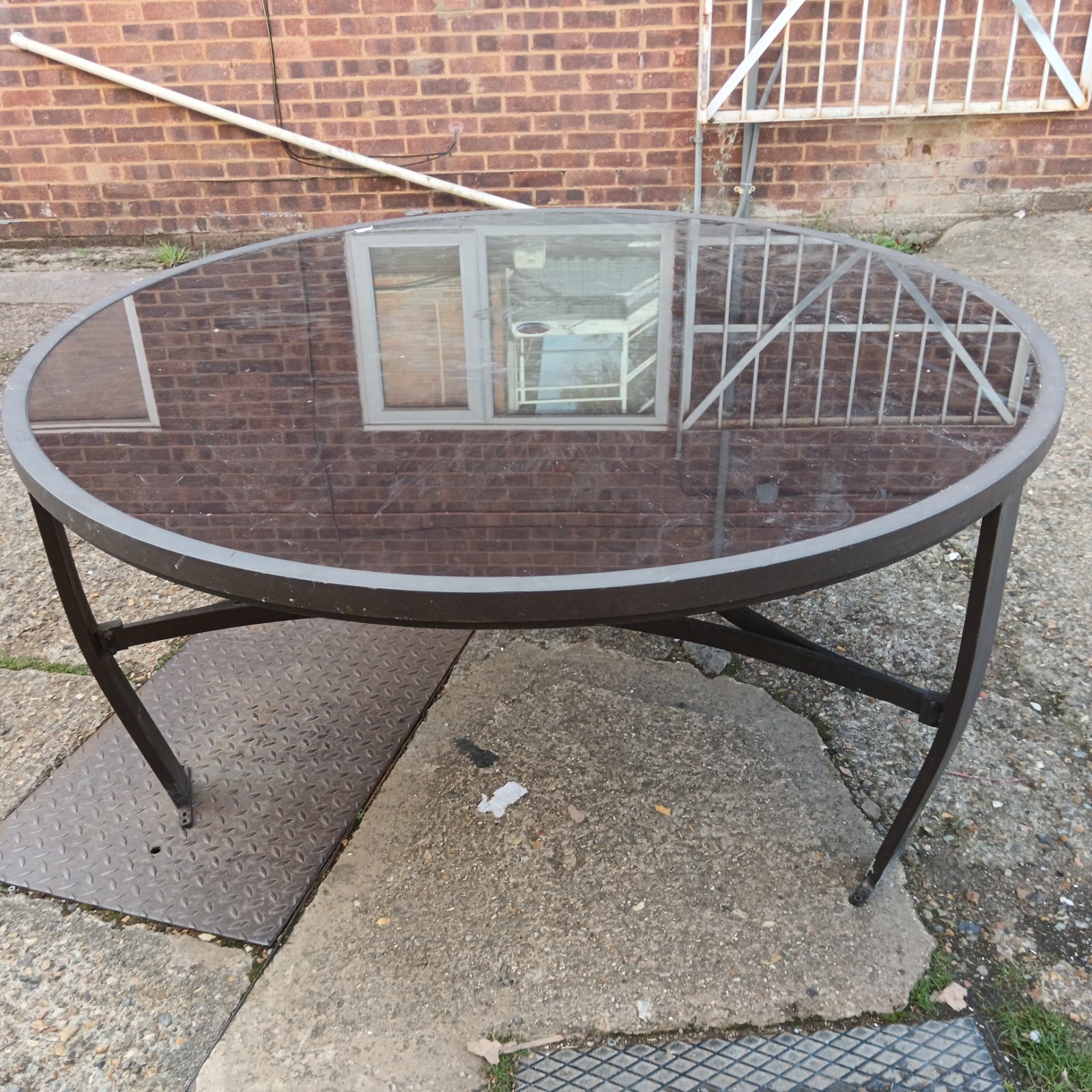 Large round glass topped garden table in a garden setting.