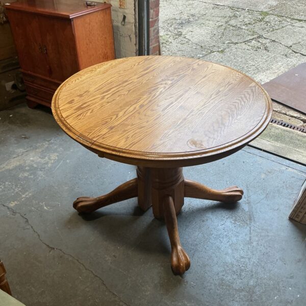 Round oak pedestal dining table with carved claw and ball feet