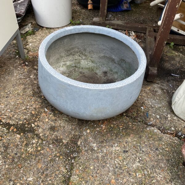Round stone effect garden planter in an outdoor setting.