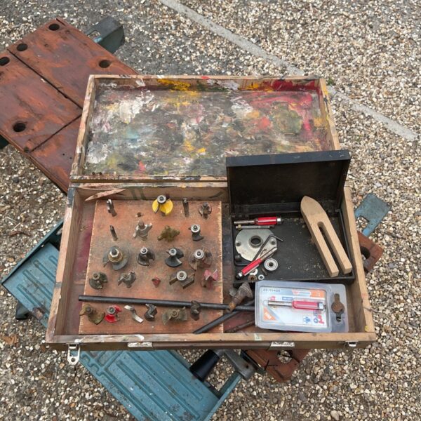 Vintage router bit set displayed in a worn wooden box.