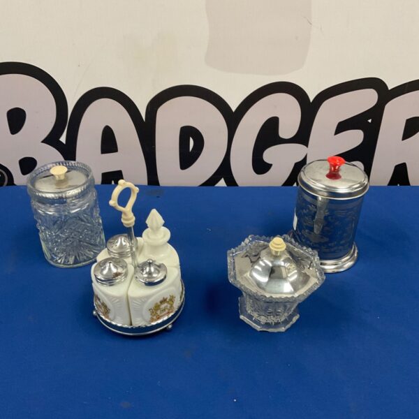 White opaline condiment set with chrome stand beside glass and metal lidded pieces