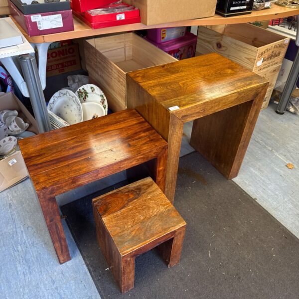 Three chunky rustic wooden side tables grouped together on a shop floor