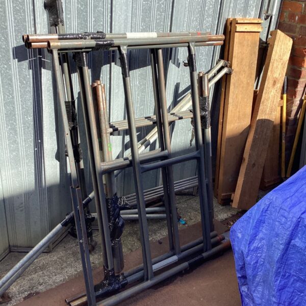 Aluminum scaffolding tower kit partially disassembled for construction work.