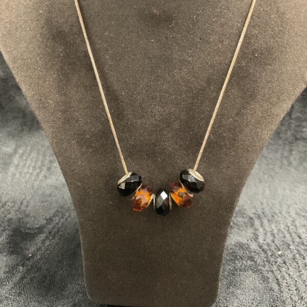 Silver necklace with amber and black beads on a snakelink chain.