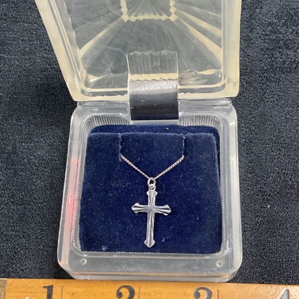 Silver cross necklace with a delicate chain and pendant.