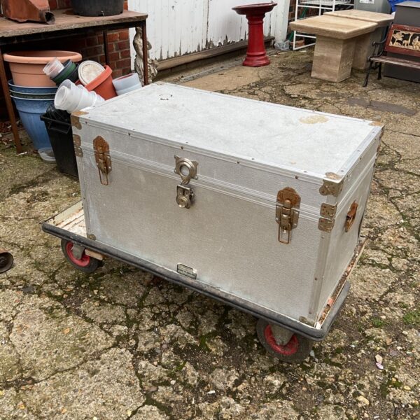 Silver metal storage box with latches on a wheeled trolley, outdoors