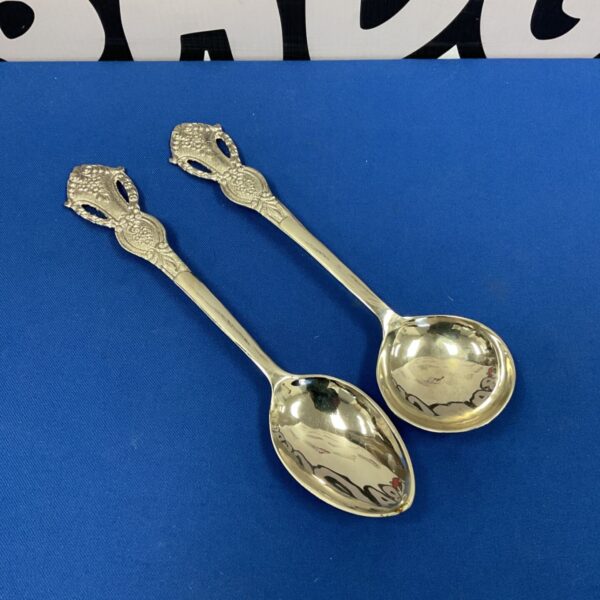 Ornate continental silver serving spoons with embossed detailing.