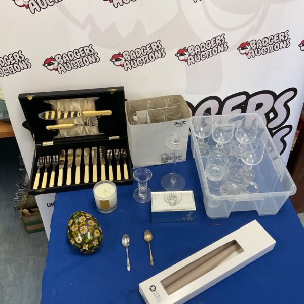 Vintage silverplate fish knife set and assorted glasses on display.