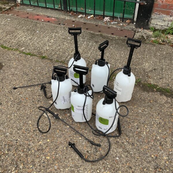 Six used hand pump sprayers for garden and plant care.