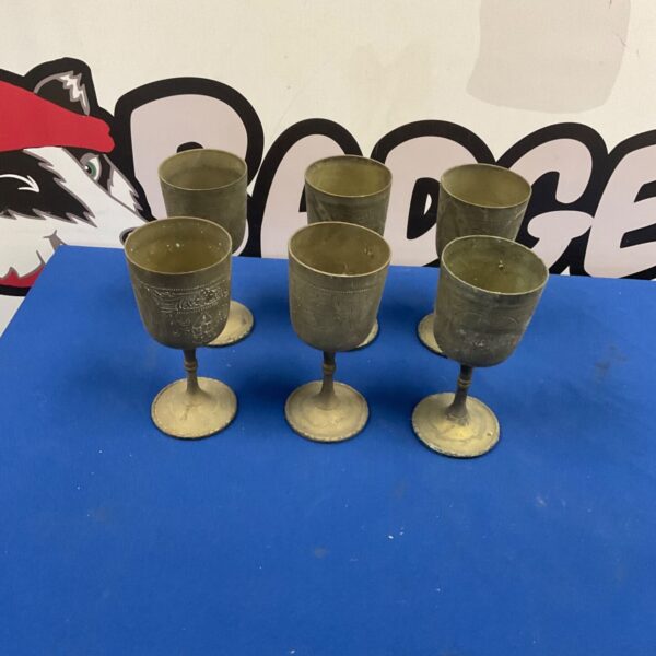 Six silverplate chalices with etched bowls arranged on a blue surface