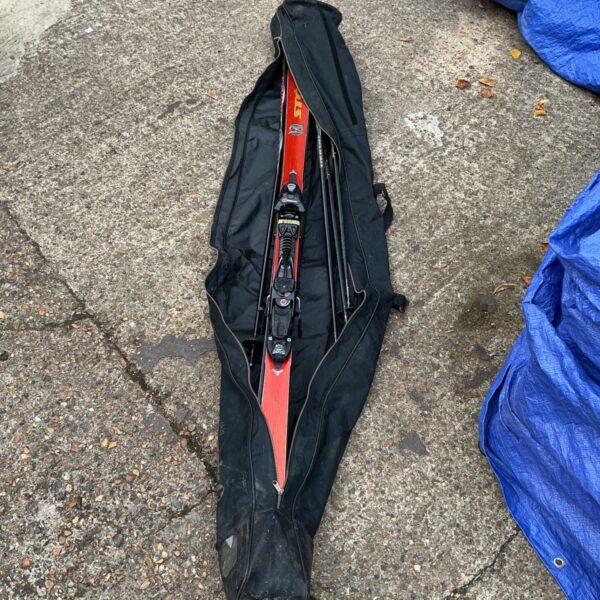 Black ski bag containing a set of skis and poles.
