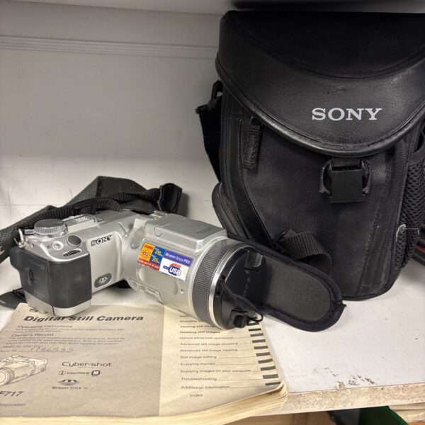 Silver Sony DSC-F717 Cyber-shot digital camera beside black Sony carry case